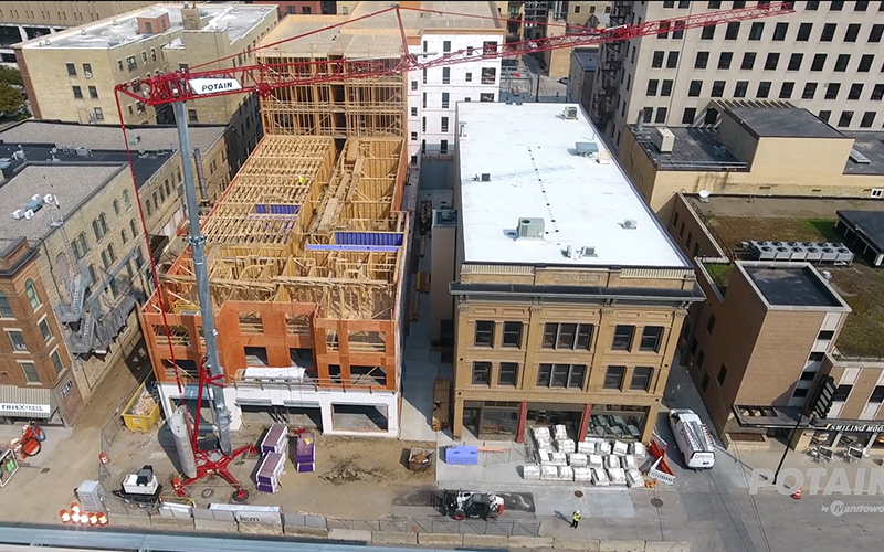 Potain Hup self-erecting tower crane on compact downtown commercial construction site showing tight footprint clearance