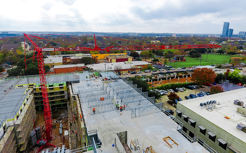 otain Igo T 85A self-erecting tower crane erected on multi-story urban residential construction site with extended telescoping lattice mast 